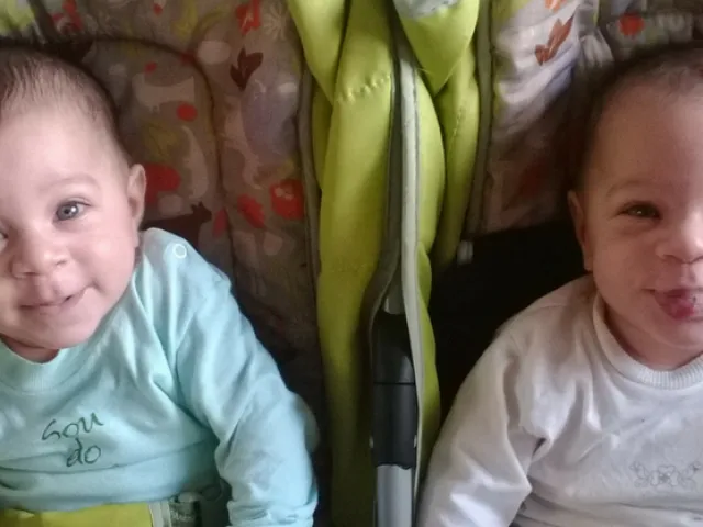 Bebes gemelos sentados en sus coches sonriendo.